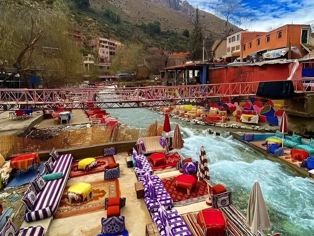 Cafés colorés au bord de la rivière et passerelle piétonne dans la vallée de l'Ourika