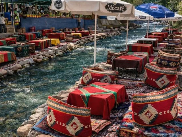 Tables de café au bord de la rivière et places assises colorées dans la vallée de l'Ourika