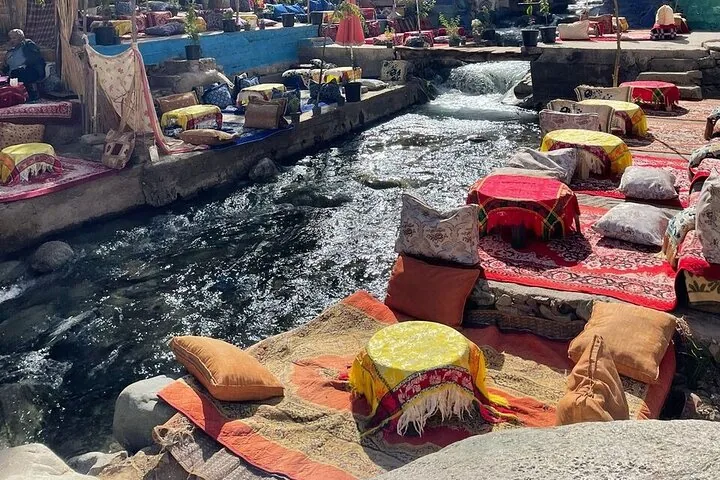 Assises au bord de la rivière avec coussins et tapis dans la vallée de l'Ourika